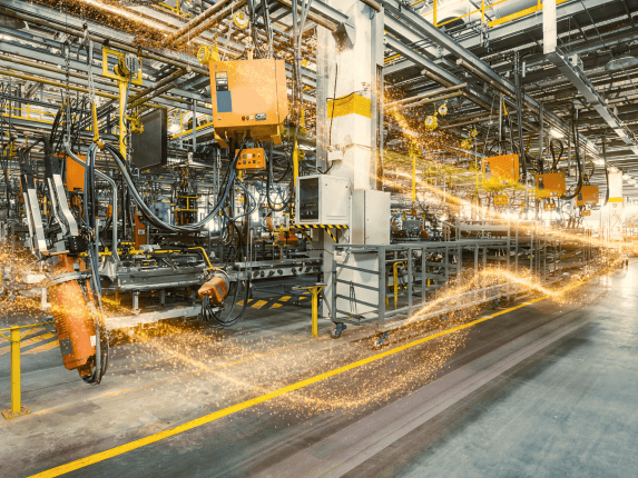 Industrieroboter in einer Fertigungshalle, umgeben von Funkenflug während der Arbeit