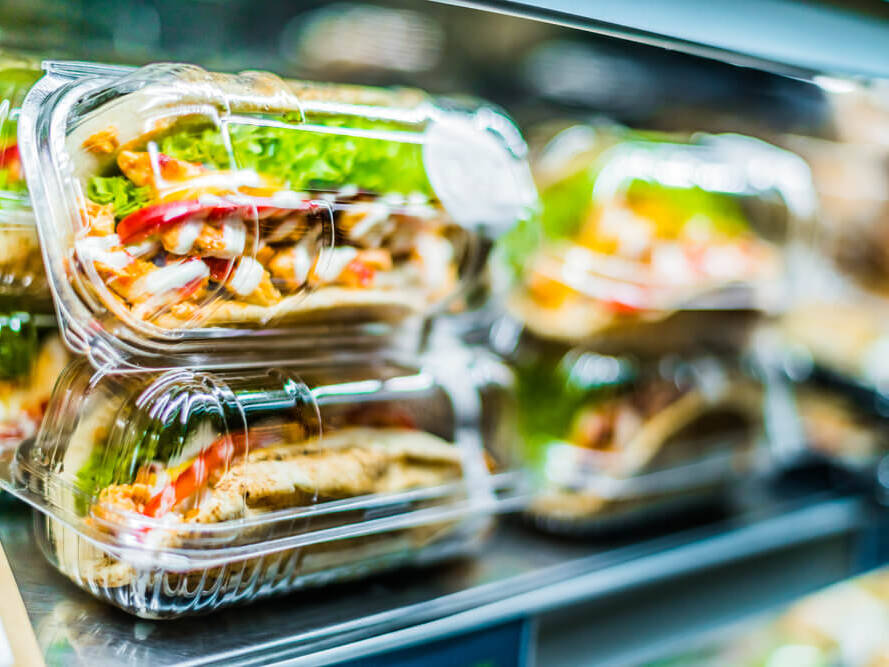 Mehrere durchsichtige Plastikbeh&auml;lter mit gemischtem Salat und Gem&uuml;se in einem K&uuml;hlregal