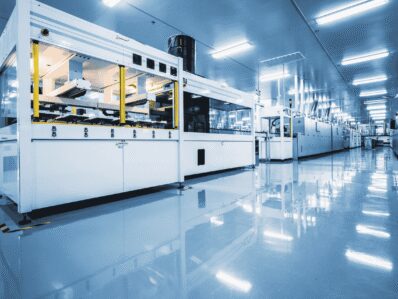 Lange Produktionsstraße mit großen weißen Maschinen in einer hell beleuchteten Fabrikhalle