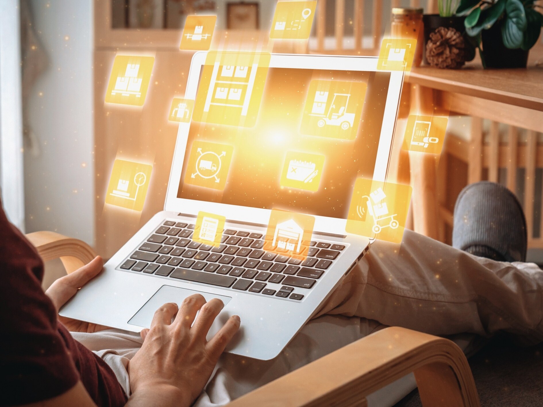 Person sitzt auf einem Sessel und bedient einen Laptop mit schwebenden, leuchtenden Icons &uuml;ber der Tastatur